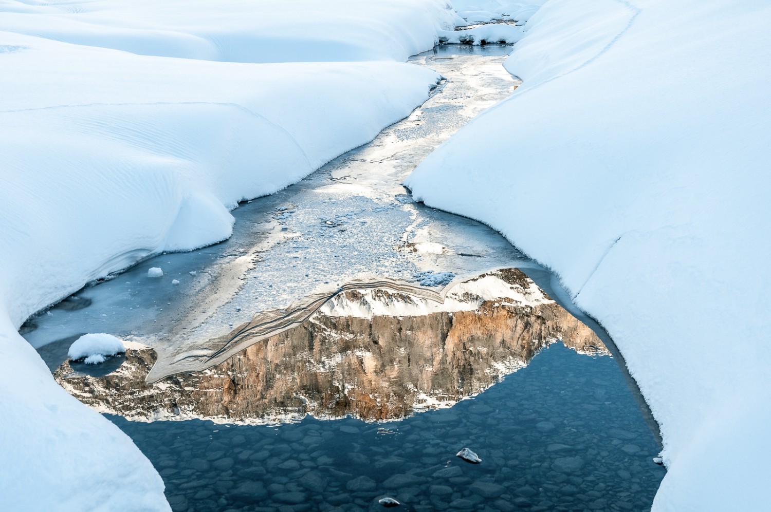 Malgré le froid hivernal, l’eau subsiste par endroits, offrant un joli reflet des montagnes. Photo: Fredy Joss